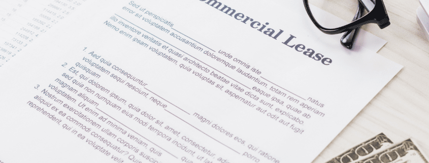 commercial lease document with money and glasses sitting on desk