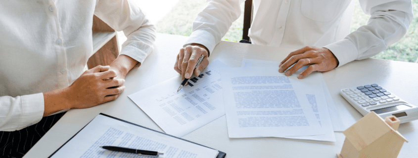 two professionals sitting at a desk reviewing paperwork