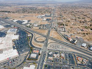 Victorville, California – April 15, 2021: aerial drone view of Victorville above freeway 15 and Bear Valley Rd with shopping malls, commercial buildings, and vacant lands.