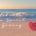 Celebrate the Spirit of Giving overlayed on a beach photo with a red heart on the sand