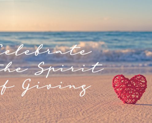 Celebrate the Spirit of Giving overlayed on a beach photo with a red heart on the sand