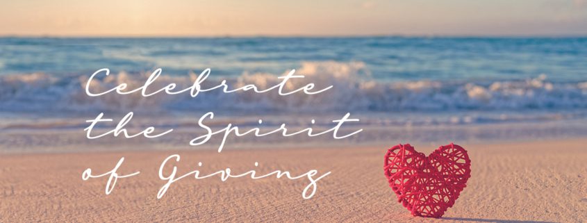 Celebrate the Spirit of Giving overlayed on a beach photo with a red heart on the sand