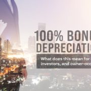 100 percent bonus depreciation text on image of man holding cash superimposed on city skyline