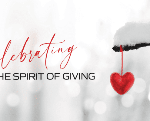 Celebrating the Spirit of Giving on a snowy background with a red heart ornament hanging from a tree branch