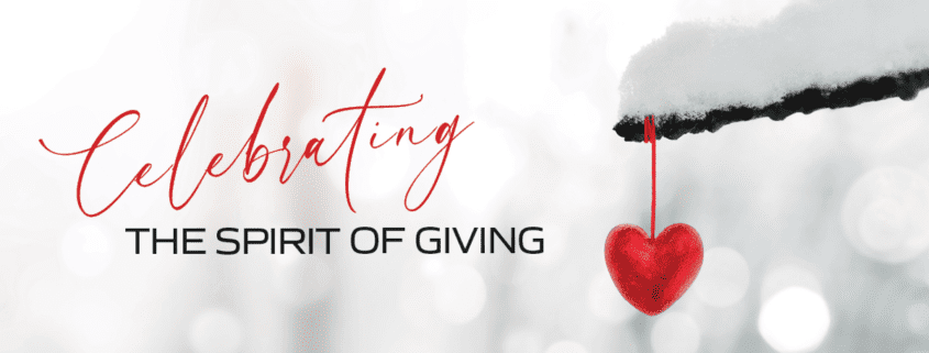 Celebrating the Spirit of Giving on a snowy background with a red heart ornament hanging from a tree branch