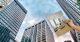 hand holding an apartment rendering over an office buildings pending conversion to multifamily housing