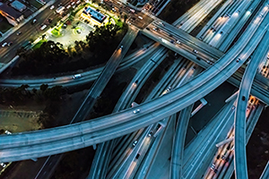 Aerial view of a massive highway in Los Angeles, CA at night with young woman holding out a smartphone in her hand