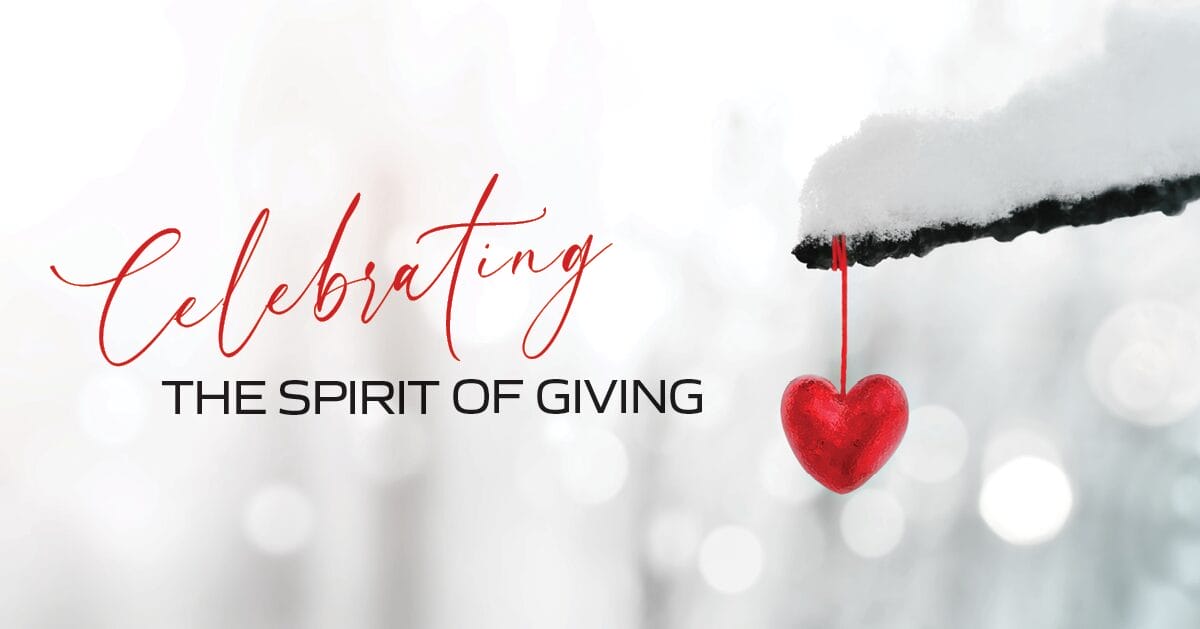 Celebrating the Spirit of Giving on a snowy background with a red heart ornament hanging from a tree branch